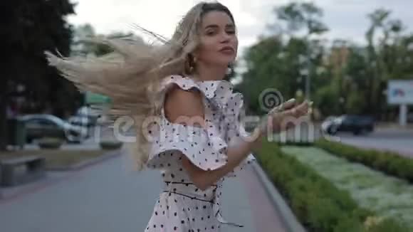 美丽的幸福女人穿着裙子在夏天的城市吹着空气的吻慢动作视频的预览图