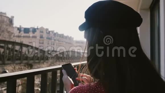 后景特写幸福美丽的创意工女使用智能手机在田园阳光的巴黎阳台度假视频的预览图
