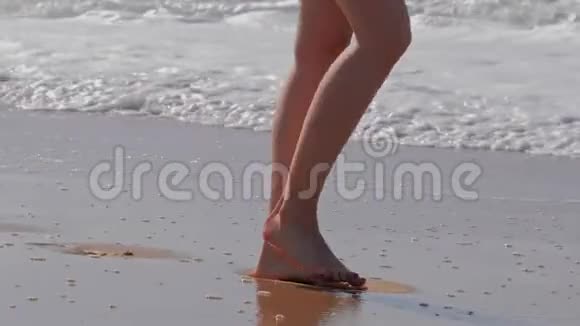在沙滩上散步的女人海洋泡沫波的特写细节视频的预览图