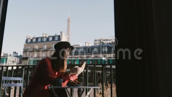 在田园诗般的阳光明媚的早晨巴黎咖啡馆露台上相机在房间窗户后面滑动着快乐优雅的女人使用智能手机视频的预览图