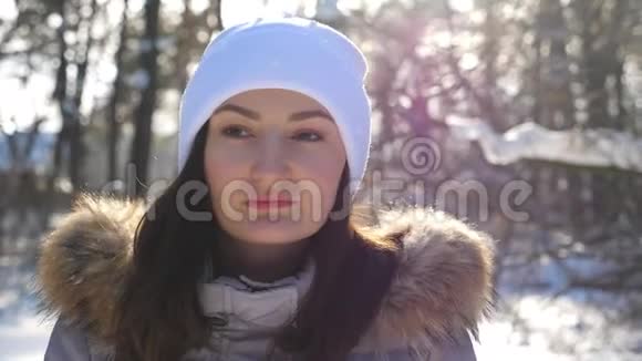 黑发女人行走和欣赏美丽的冬季景观的肖像女孩穿过白雪皑皑的森林视频的预览图
