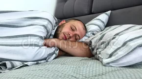 男人一个人睡在毯子下面的床上侧视视频的预览图