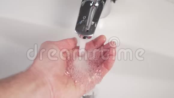 一个漂亮的浴室水龙头里的水被倒进男人的手里形成气泡和飞溅视频的预览图