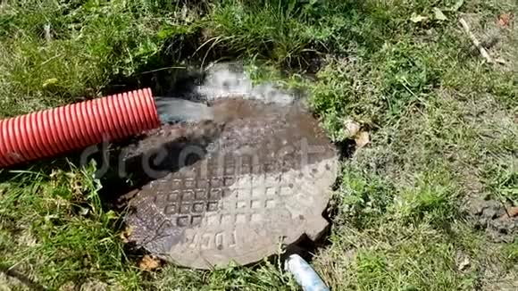 从红色波纹管中流出的水从排水沟中流出水在流动雨水从管道里流出来掉下来废物处理视频的预览图