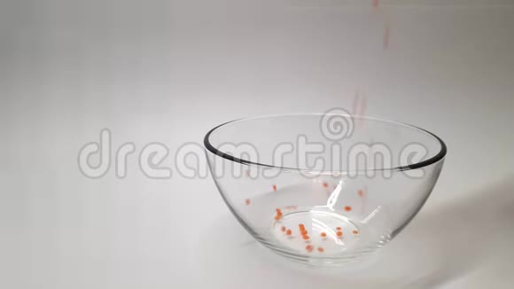 橙豆倒入透明玻璃器皿中白色背景视频的预览图
