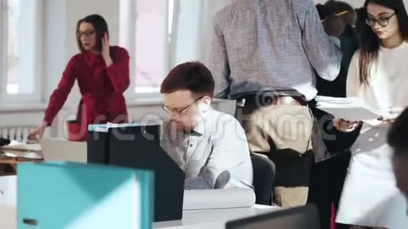 年轻的高加索商人经理在繁忙的现代办公室工作压力很大疲惫不堪女人把文件放在他的桌子上视频的预览图