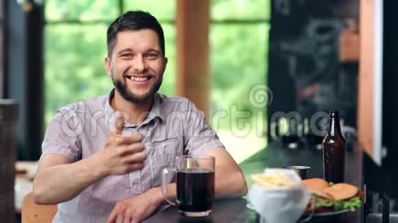 快乐积极的人在酒吧喝啤酒和快餐显示拇指冷静的手势中弹视频的预览图