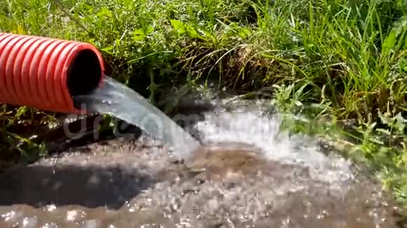 从红色波纹管中流出的水从排水沟中流出水在流动雨水从管道里流出来掉下来废物处理视频的预览图