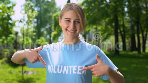 微笑的女性指着t恤上的志愿者单词森林保护地球视频的预览图