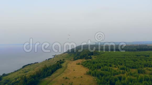 森林海岸线和一个公羊空降落伞沿着它飞行空中滑翔伞视频的预览图