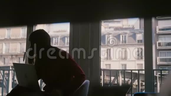 漂亮专注的年轻女商人使用笔记本电脑在巴黎的公寓窗口打电话火车经过视频的预览图