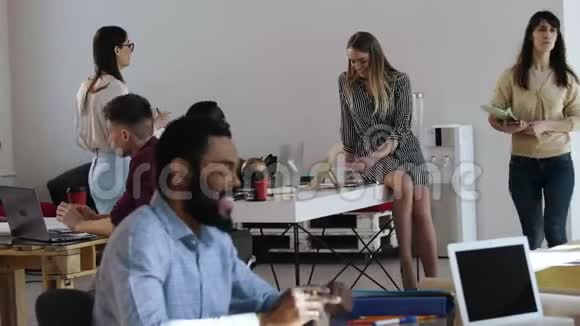 快乐的年轻积极的非洲男人穿着正式的衬衫微笑着参加一个工作面试坐在时尚的现代阁楼办公桌上视频的预览图
