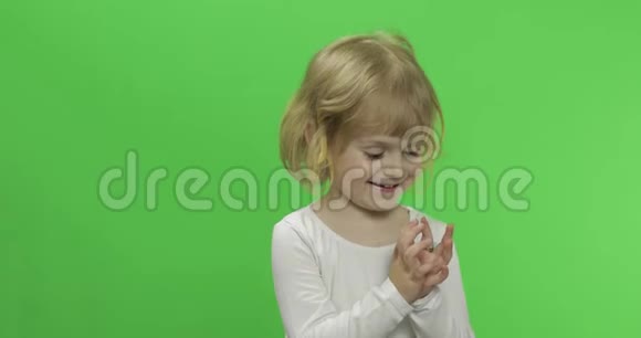 穿白色t恤的快乐金发小女孩可爱的金发孩子做鬼脸视频的预览图