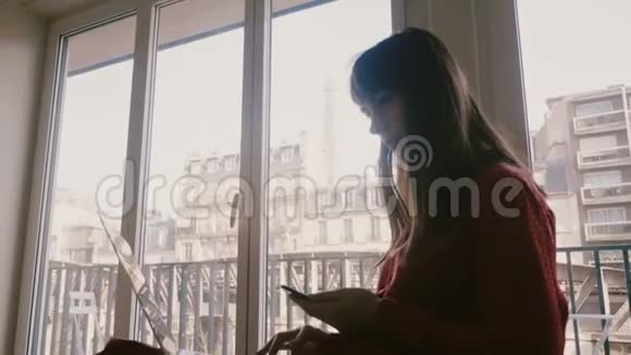 成功自信的年轻女商人在巴黎酒店窗口用笔记本电脑和智能手机微笑火车经过视频的预览图