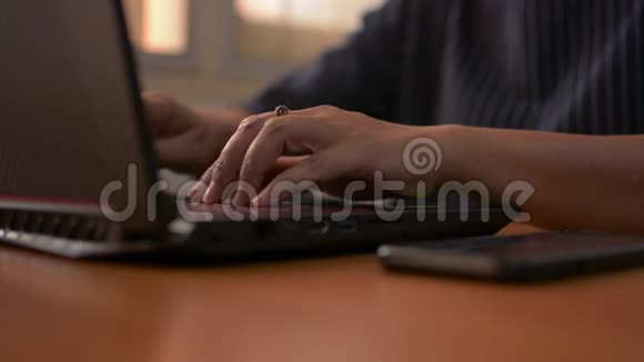 女人的手在电脑键盘上打字用手机女商人在办公室里用笔记本电脑工作视频的预览图