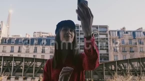 快乐美丽微笑的旅游女人在巴黎的房间阳台上用埃菲尔铁塔景拍摄智能手机自拍照片视频的预览图