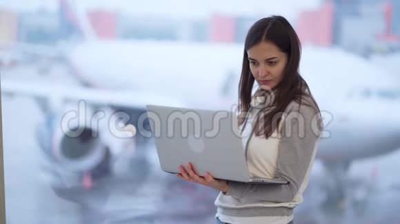 在机场窗户附近工作的女人背景模糊的飞机视频的预览图