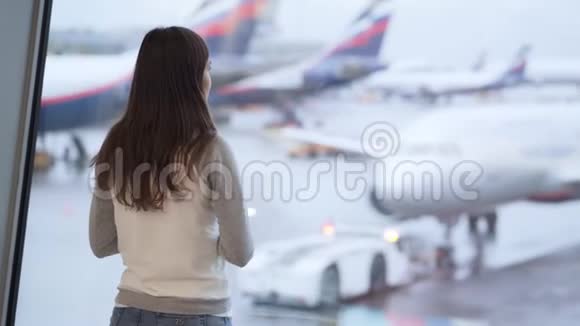 站在机场候机楼的女性的背面看窗外的飞机视频的预览图