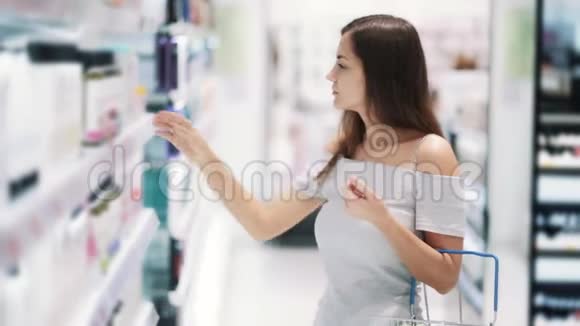 化妆品店里的女人选择淋浴凝胶阅读标签嗅它慢动作视频的预览图