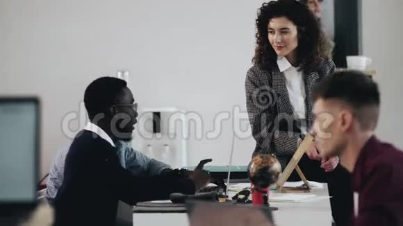 快乐职业年轻有吸引力的商业导师女教授两个黑人男性经理在现代阁楼办公桌视频的预览图