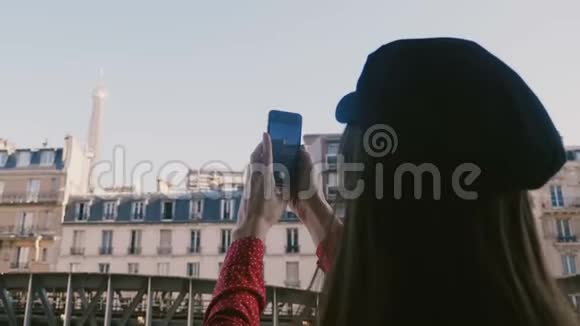 镜头滑到快乐女游客后面从公寓阳台上拍摄巴黎埃菲尔铁塔的智能手机照片视频的预览图