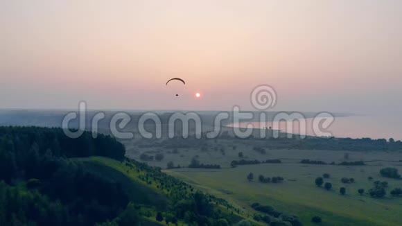 日落时绿树成荫帆翼在上面飞翔空中滑翔伞视频的预览图