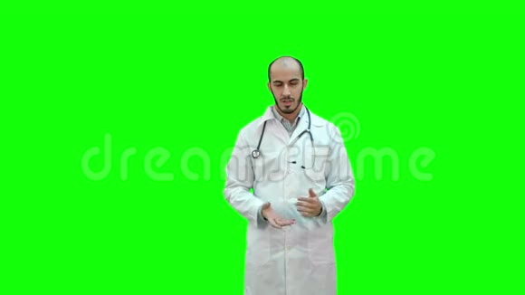严肃的男医生在绿色屏幕上与摄像机交谈Chroma键视频的预览图