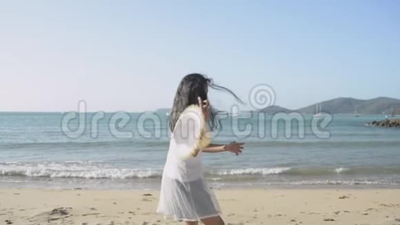 亚洲可爱的女孩跑去收集一顶草帽这顶草帽是在阳光下被海滩上的风吹着的视频的预览图
