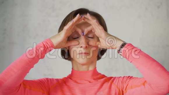 成年妇女用手戴眼镜面部按摩前照相机特写女人做皮肤面部按摩抗老化视频的预览图