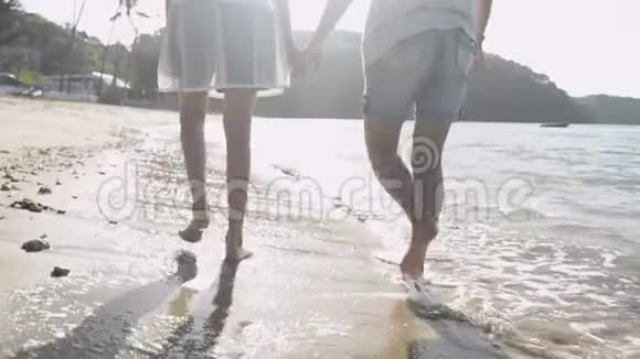 夏天妈妈和女儿一起在阳光下快乐地在海滩上散步和牵手视频的预览图