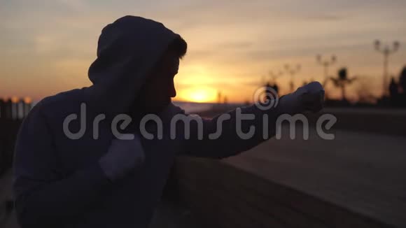 日落时分男子拳击手独自在露天运动场与空气搏斗视频的预览图