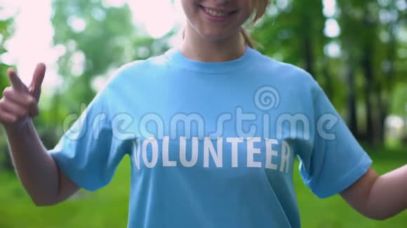 开朗的年轻女性指着t恤上的志愿者词责任视频的预览图