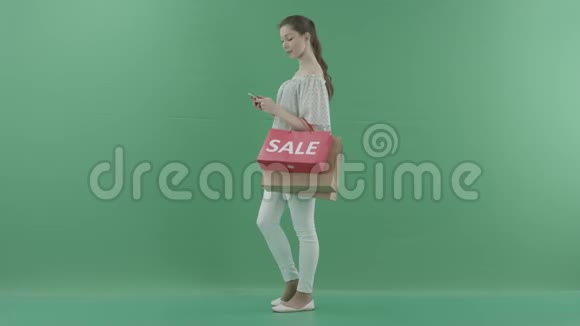 女人站在个人资料和使用智能手机和观看某人在绿色屏幕视频的预览图