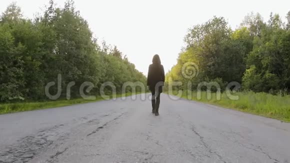 一个穿着黑色羊毛衫带着头罩的白人正在一条乡间小路的中间路上环绕着沥青视频的预览图