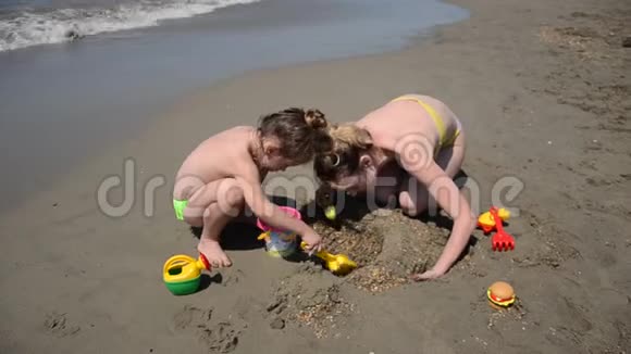 年轻的母亲和她的小女儿在沙滩上玩耍用沙子建造雕像和城堡视频的预览图
