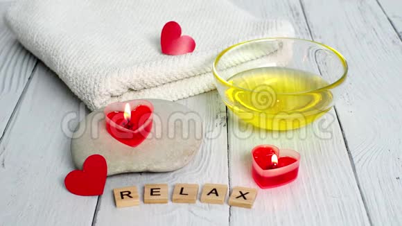 情人节水疗概念燃烧红色心形蜡烛石头按摩油单词放松和白色毛巾视频的预览图