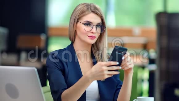 时尚微笑的商务女性戴着时尚眼镜聊天使用智能手机享受休息视频的预览图