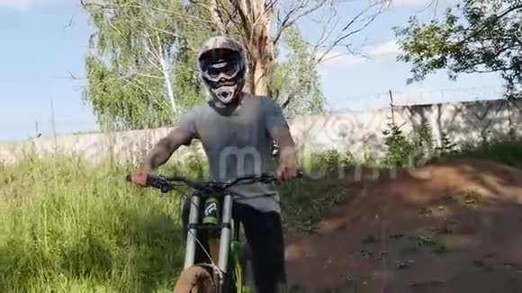 戴着安全帽的年轻人骑着山地自行车在夏日森林的山上视频的预览图