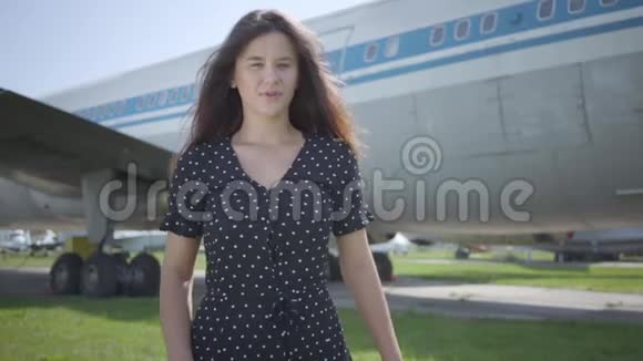 年轻的黑发女孩穿着黑色裙子的白色披肩在大飞机前转身离开夏日周末快乐视频的预览图