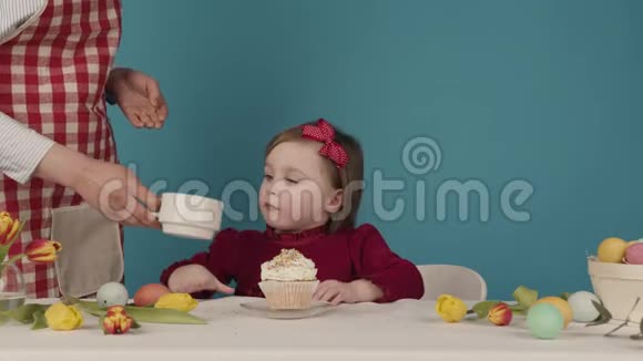 为复活节准备蛋糕的女孩洒上五颜六色的糖果复活节快乐视频的预览图