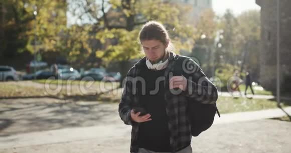 年轻人在街上走路时用手机人类正在使用他的智能手机进步技术社会网络视频的预览图