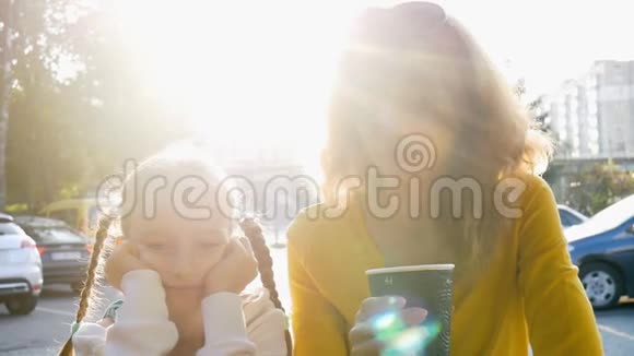 年轻的母亲穿着黄色衬衫端着一次性的咖啡小可爱的女儿正早早地坐在那里聊天视频的预览图