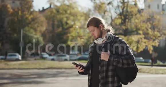 人们在城市里使用智能手机上的应用程序英俊的年轻人自信地在智能手机上交流城市男性视频的预览图