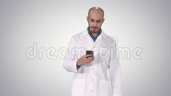 男性阿拉伯医生在渐变背景下行走时在电话上发短信视频的预览图