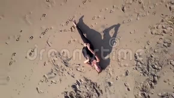 穿运动服的运动女孩在沙滩上伸腿视频的预览图