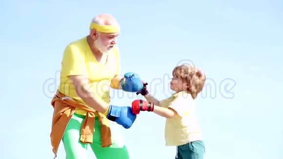 一个坚定的资深拳击手的肖像带着一个小男孩的孩子在蓝天的背景下年纪大点的拳击帅哥视频的预览图