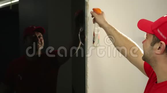 一个男人一个戴着红色帽子的建筑工人在黑色玻璃门上喷洒液体视频的预览图