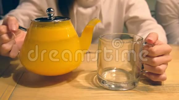 女人正从茶壶往杯子里倒沙棘凉茶双手特写视频的预览图