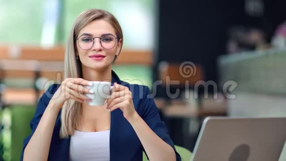 可爱的欧洲商界女性戴着眼镜端着咖啡杯在中档咖啡馆休息视频的预览图