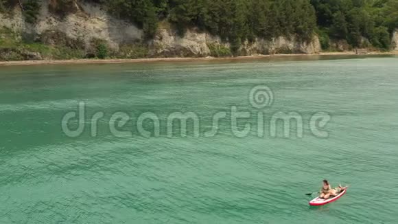 超级冲浪女人在冲浪板上划船美丽的海景有人躺在船上视频的预览图